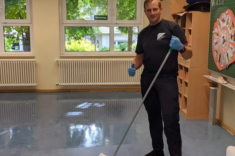 Mitarbeiter wischt den glänzenden Boden eines hellen Gruppenraums