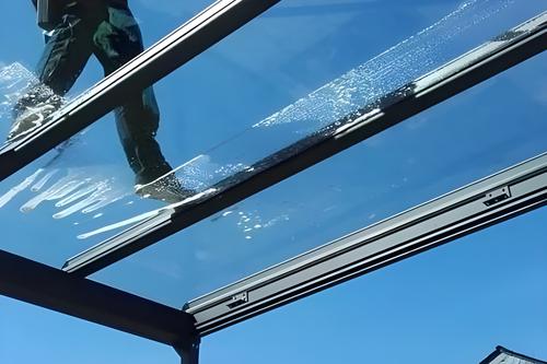 Mitarbeiter reinigt ein Glasdach, von unten gesehen