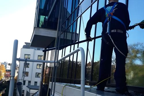 Mitarbeiter mit Sicherungsgurt reinigt eine Glasfassade