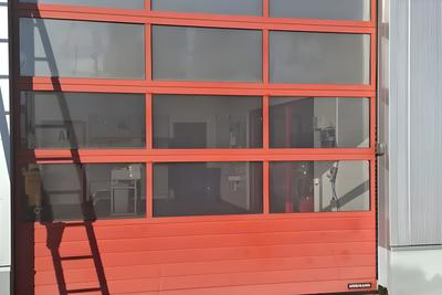 Rotes Rolltor mit Glaseinsätzen an einer Halle
