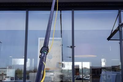 Schaufenster wird mit einer Teleskopstange gereinigt